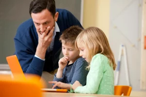 Teacher with pupils using laptop in classroom